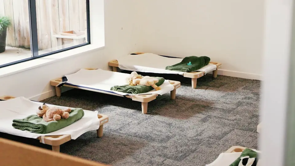 Low rest beds made up with green blankets and soft toys.