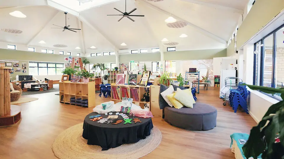 The vaulted hall, with a round table of loose parts at its centre and low shelves around it.