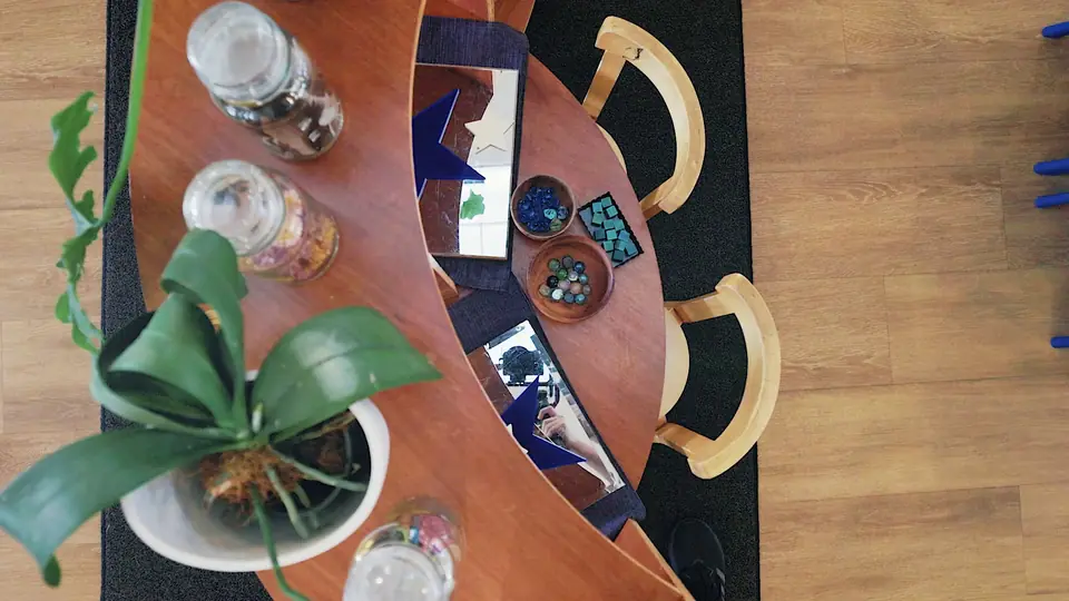 From above: a curved wooden table set with glass jars, mirrors and a potted orchid.