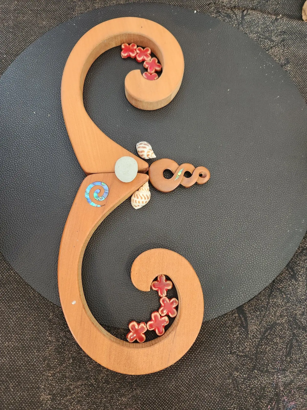 Two wooden koru shapes with flowers and a shell.