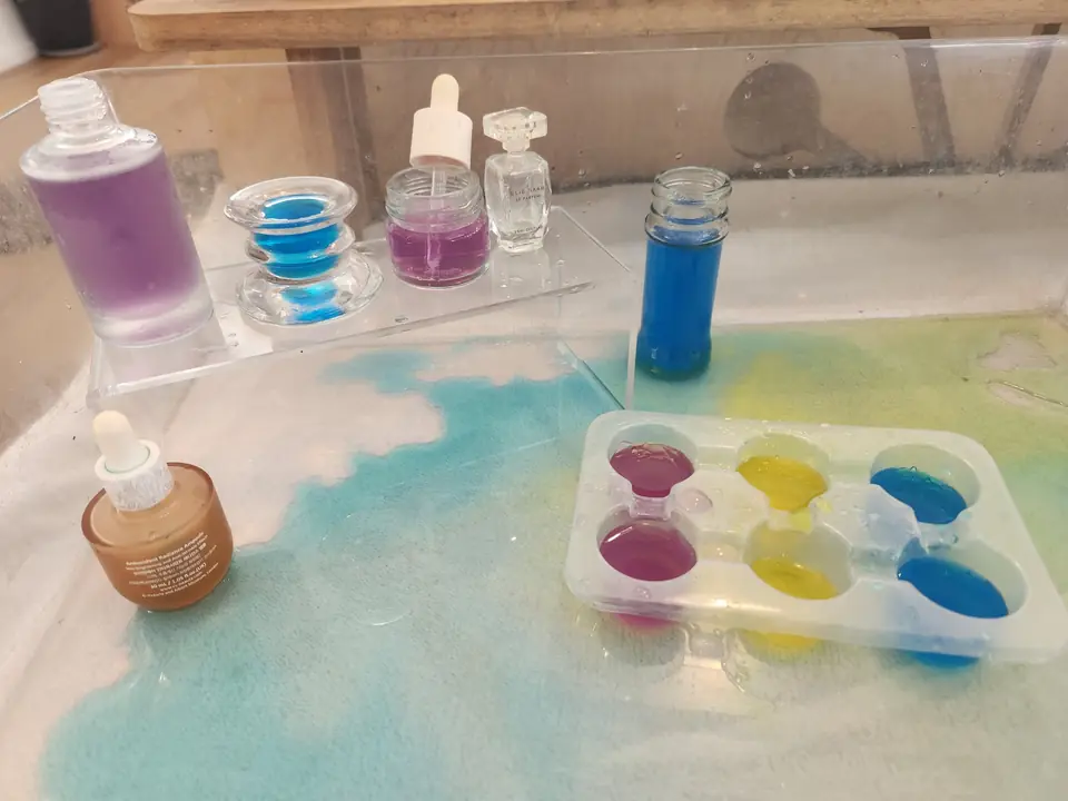 Colour mixing: droppers, small bottles and a tray of blue, pink and yellow water.