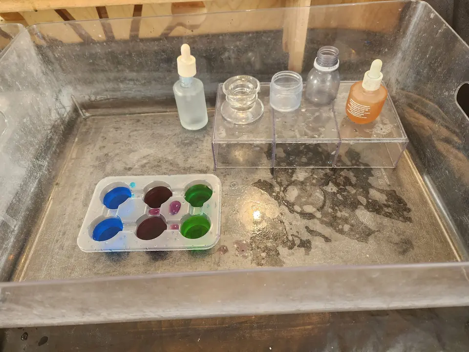 Droppers, small bottles and a paint tray on a light table.