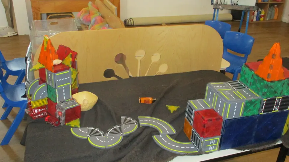 A city of magnetic tiles and road pieces on a dark mat.
