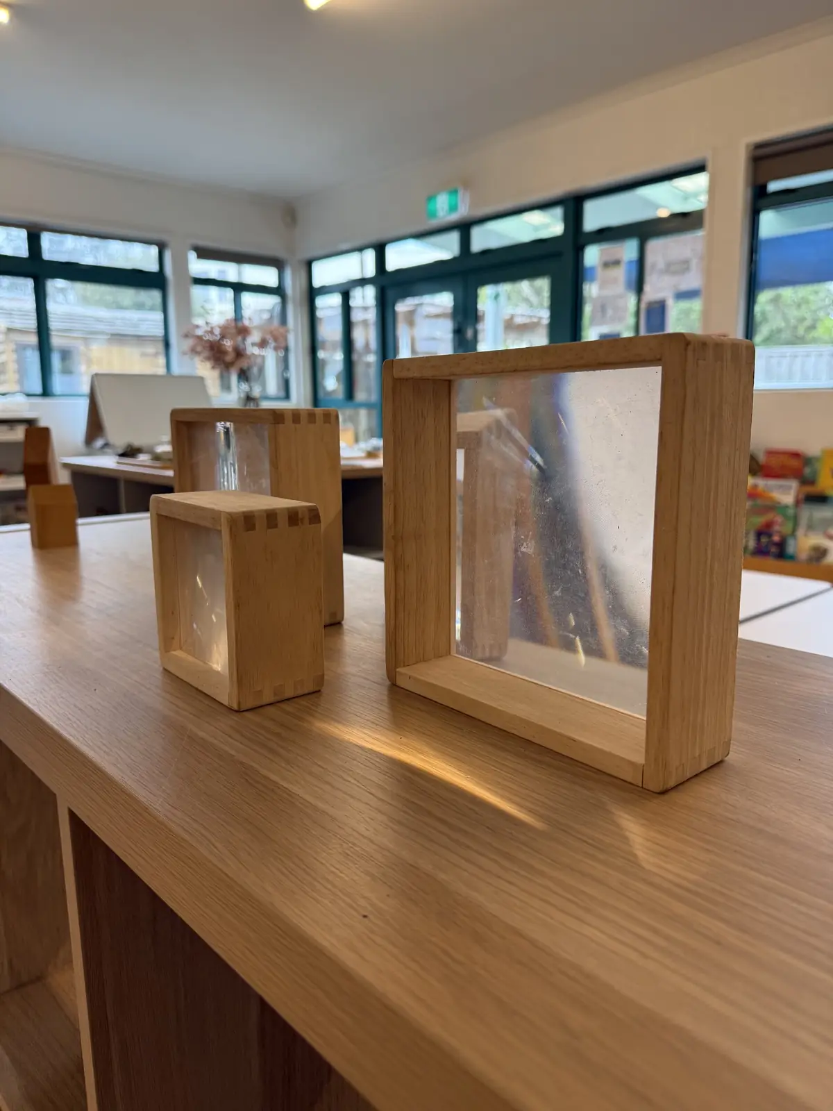 Wooden frames with clear, shimmering panels on a low shelf.